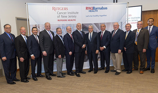 Members from RWJBarnabas Health, Rutgers Health, and the Mayor of New Brunswick, James T. Cahill in front of the rendering of the new CINJ Cancer Pavilion