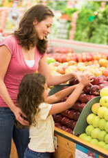 Mother and child picking an apple at the grocery store