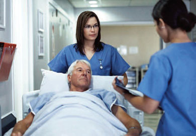 nurses moving the patient who is laying in a bed