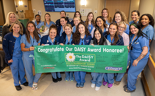 Brianna is shown front row center holding the DAISY Award banner with team members from Labor & Delivery.