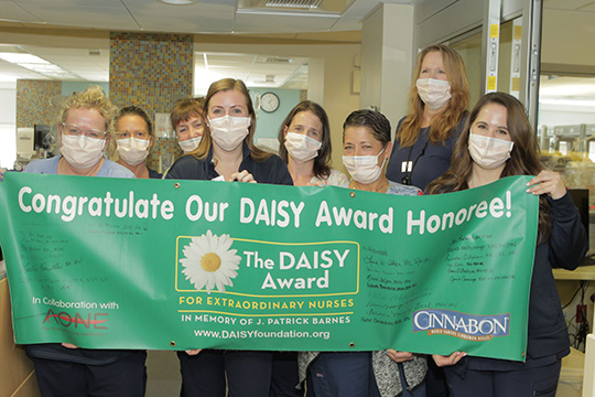 Jennifer Cavanaugh is shown with her NICU colleagues holding the signed DAISY Award banner.