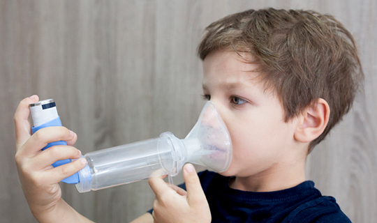 child using an inhaler with a spacer