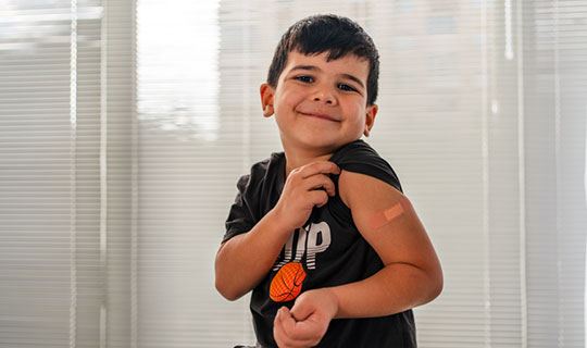 child showing band-aid after being vaccinated