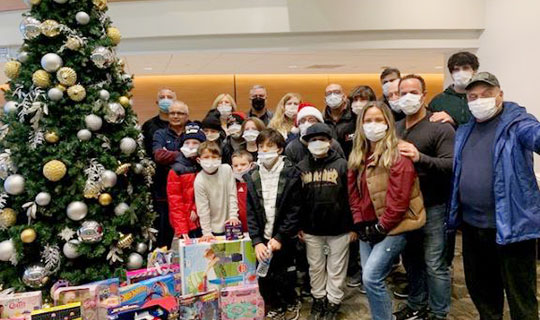 Michael and Michelle Chieffo’s annual toy drive - Clara Maass Medical Center staff with kids around the Christmas tree with all the toys