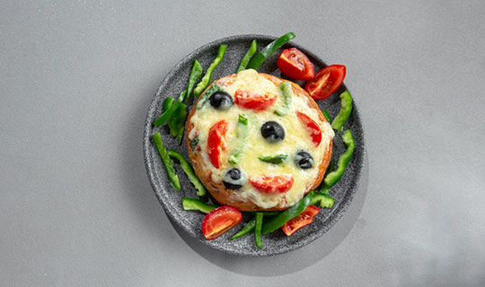 English muffin pizza with olives, peppers, and tomatoes