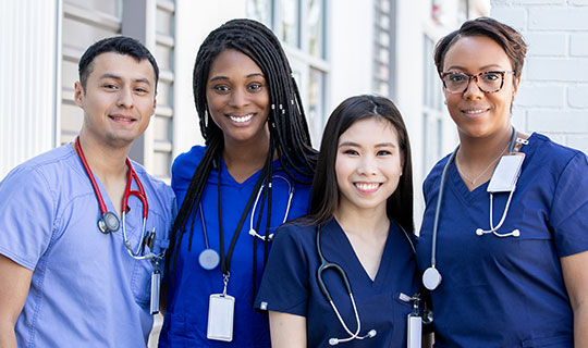 group of four diverse nurses wearing blue scrubs