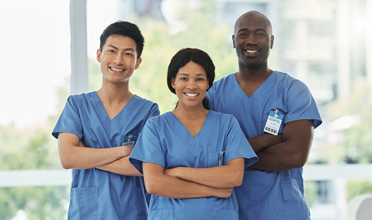 group of three nurses wearing blue scrubs