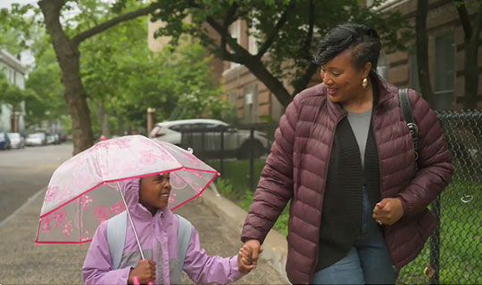 mom walking her daughter to school in the rain