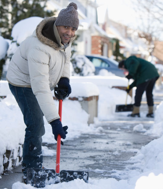 man shoveling snow on the sidewalk in front of his house