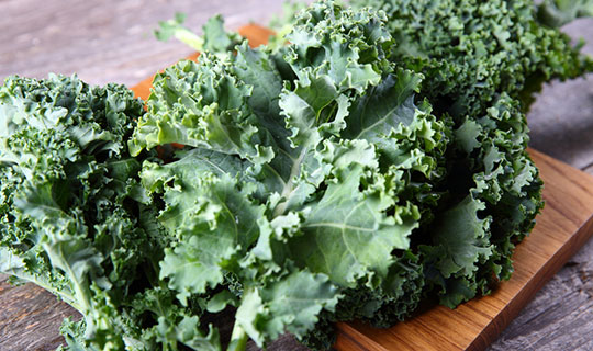 fresh kale leaves laying on a cutting board