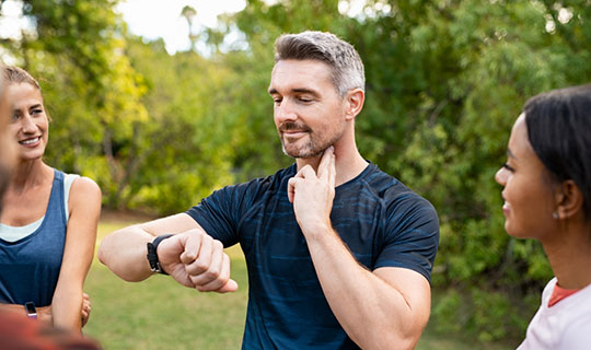 man checking his pulse after cardio workout in the park