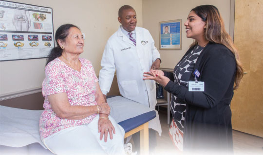 Patient navigator Punam Jain, right, helps Ravinder Soni communicate with Keiron Greaves, MD, a pain-management physician