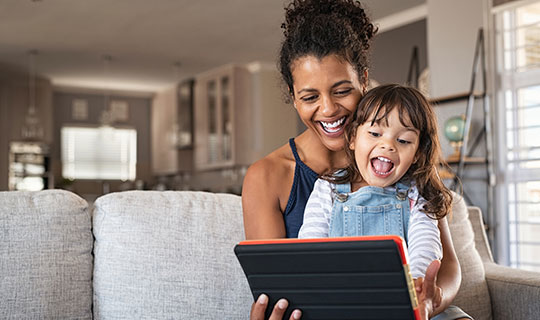 Mother with her child on her lap smiling while looking at a tablet