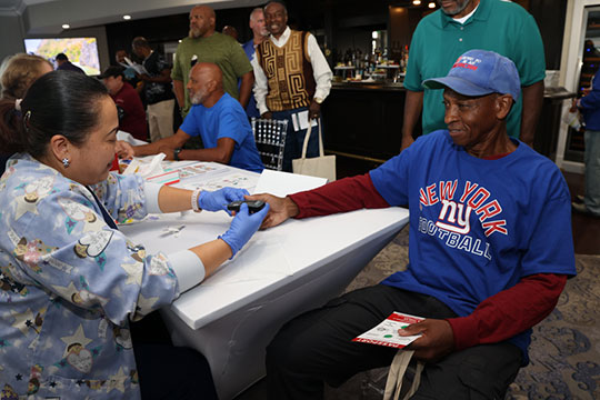 Newark Beth Israel Medical Center critical care nurse gives attendee a glucose screening