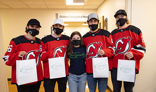 NJ Devils players with pediatric cancer survivor, Grace