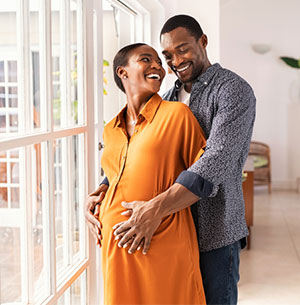 pregnant woman with her husband standing by window
