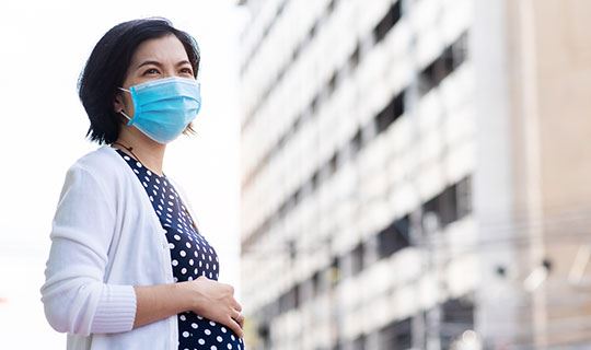 pregnant woman wearing a mask while walking in a city 