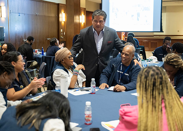 Mark E. Manigan talking with people at a table