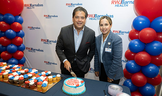 Mark E. Manigan together with Balpreet Grewal-Virk cutting a cake