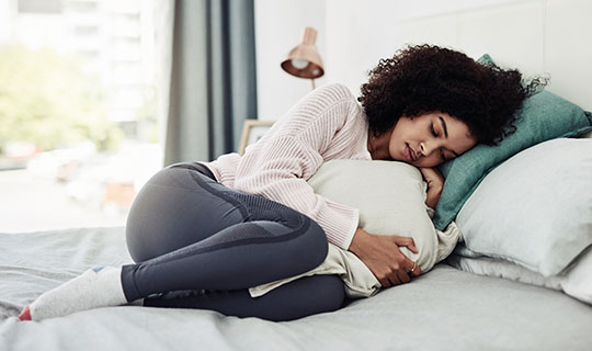 woman curled up on bed hugging a pillow
