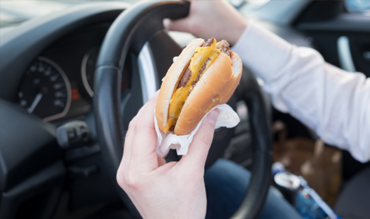 Woman Eating Cheeseburger In Car