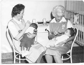 two nurses holding babies