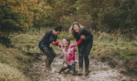 Three women laughing in the mud