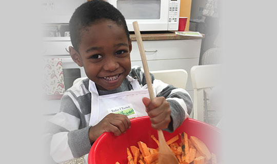 student mixing sweet potatoes in a red bowl