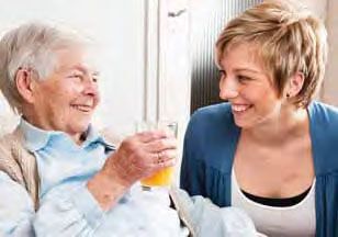 grandmother and granddaughter smiling at each other, the grandmother is holding a glass of orange juice
