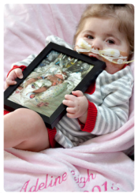 baby adeline holding picture of her as a newborn in the hospital