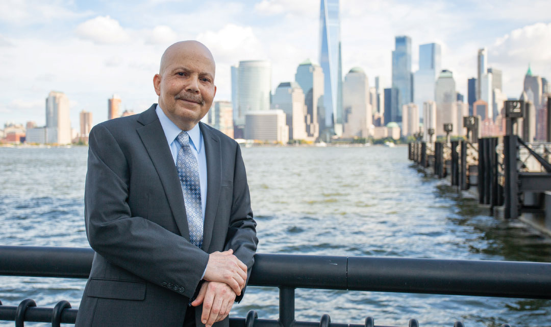 Tony Moyet standing in front of the Hudson River with the NYC skyline behind him