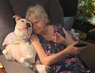 Sandra sitting on her recliner cuddling with her dog