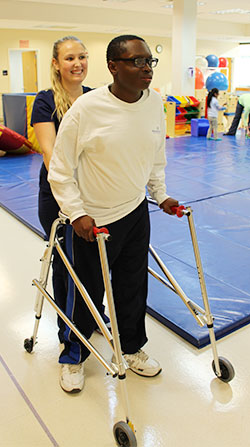 child in rehab, walking with a walker